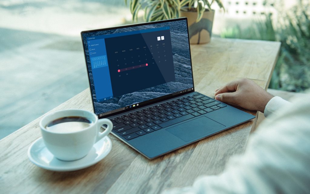 Image of an open laptop displaying a calendar, next to a cup of coffee.